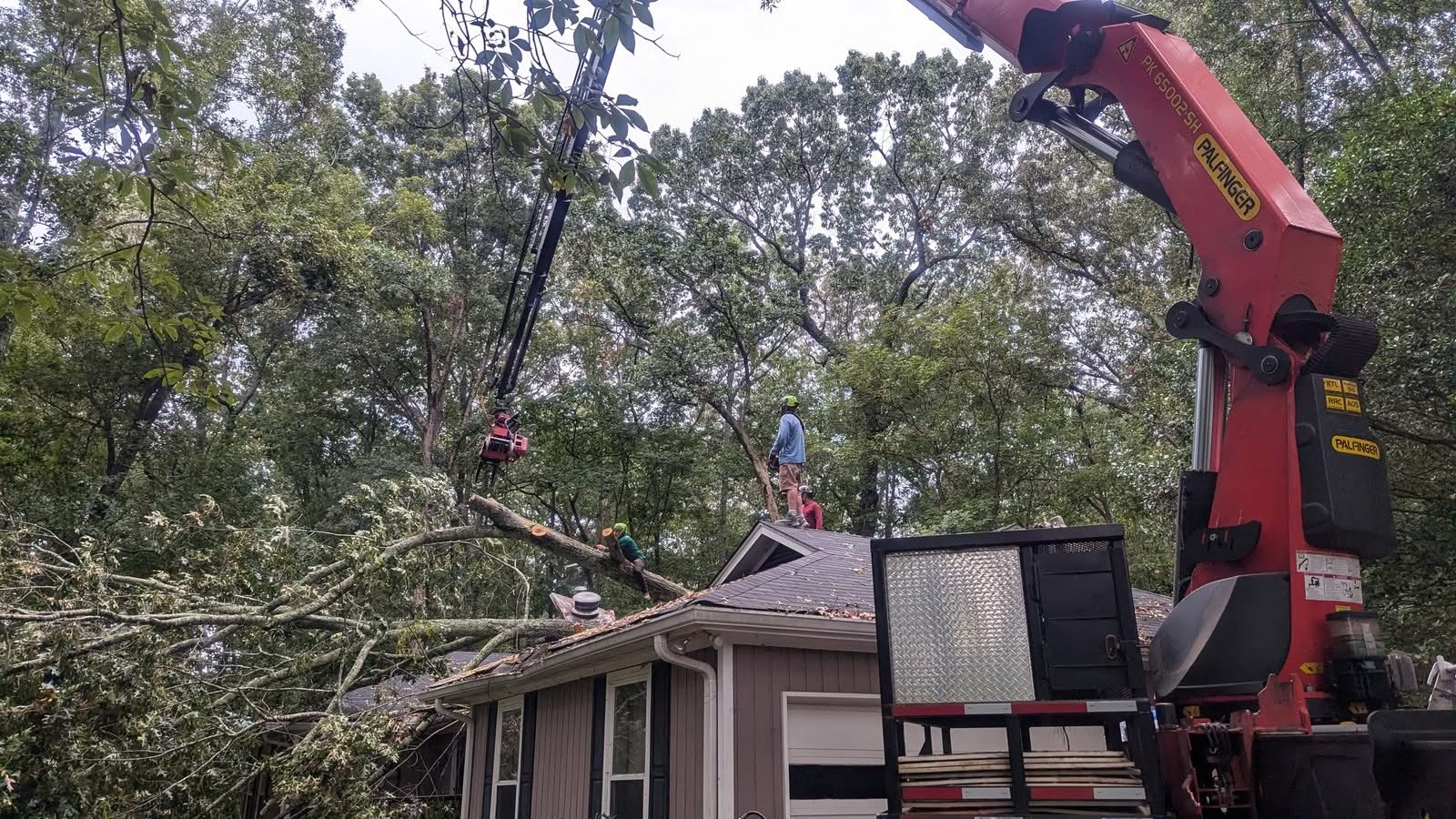 Palfinger grapple-saw crane set up over an Alpharetta GA home with a storm-fallen oak on the roof, September 2024