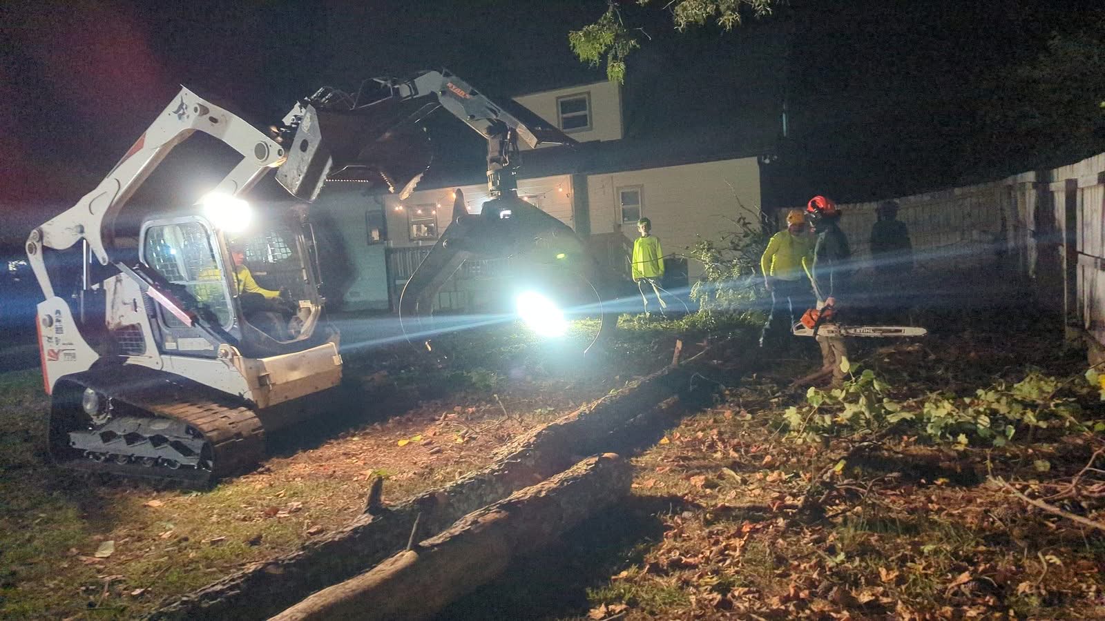 Tree removal crew and skid steer clearing a storm-fallen pine in Kennesaw GA at night, September 2024